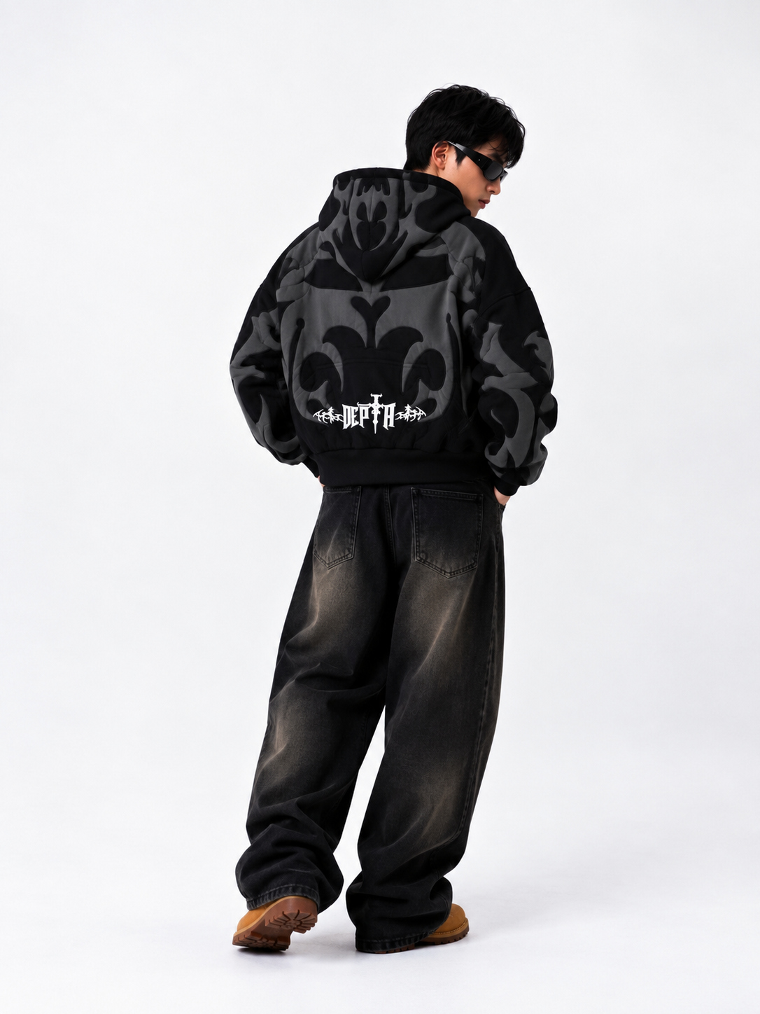Front angle showing the tactile 3D puff print graphics on the black Exotix hoodie worn by a male model