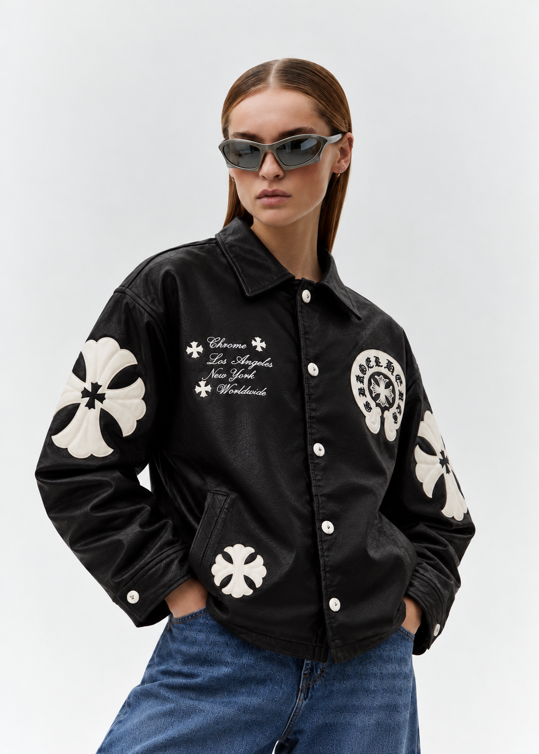 Streetwear front lifestyle angle of a girl styling the black cross patch faux leather jacket with washed wide-leg denim