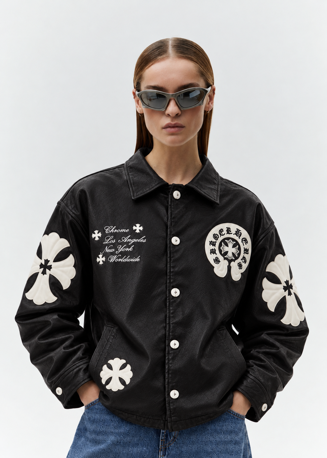 Female model wearing the unisex black Gothic cross patch leather jacket from the front, showing the clean drop-shoulder cut