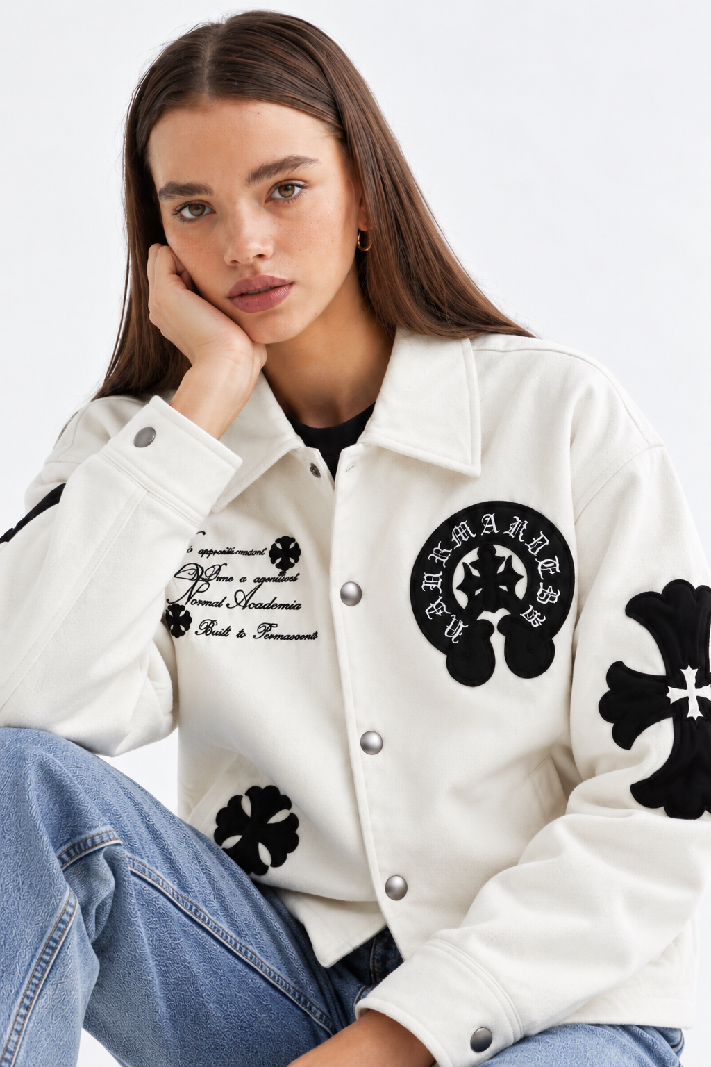 Detailed macro shot of the black leather cross appliqué with perimeter twin-needle stitching and Gothic chest script embroidery