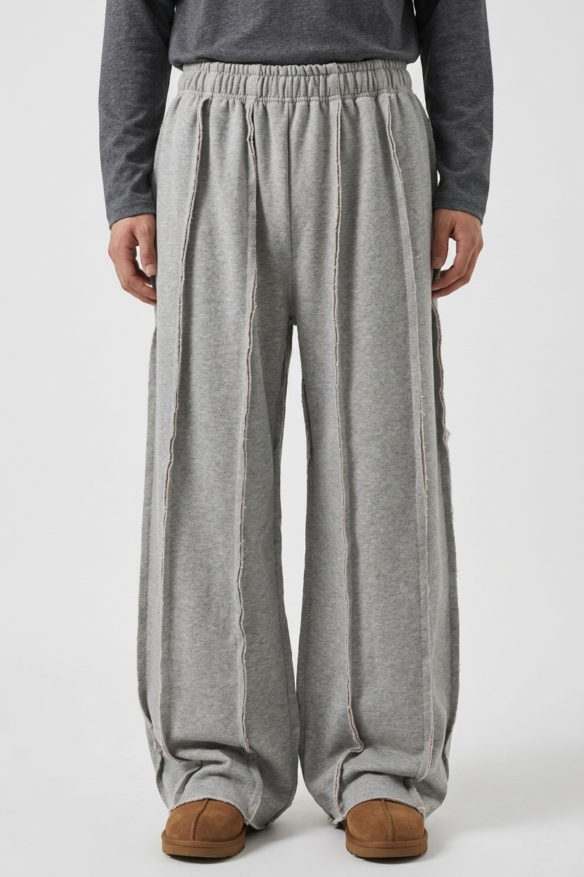 Male model wearing the baggy exposed seam sweatpants by Exotix, showcasing the relaxed streetwear fit and raw hem stacking over sneakers