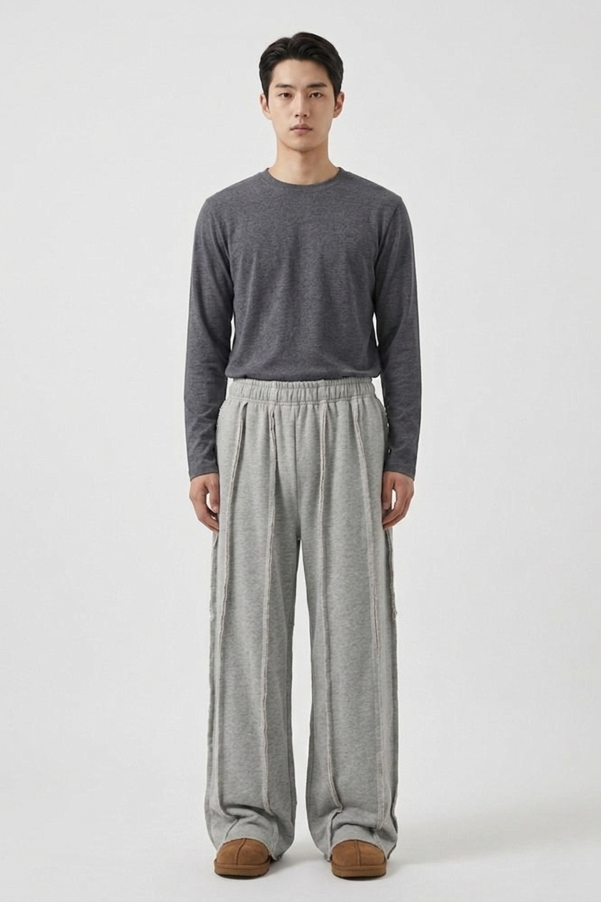 Urban streetwear lifestyle shot highlighting the wide-leg, relaxed drape of the men's exposed seam track pants