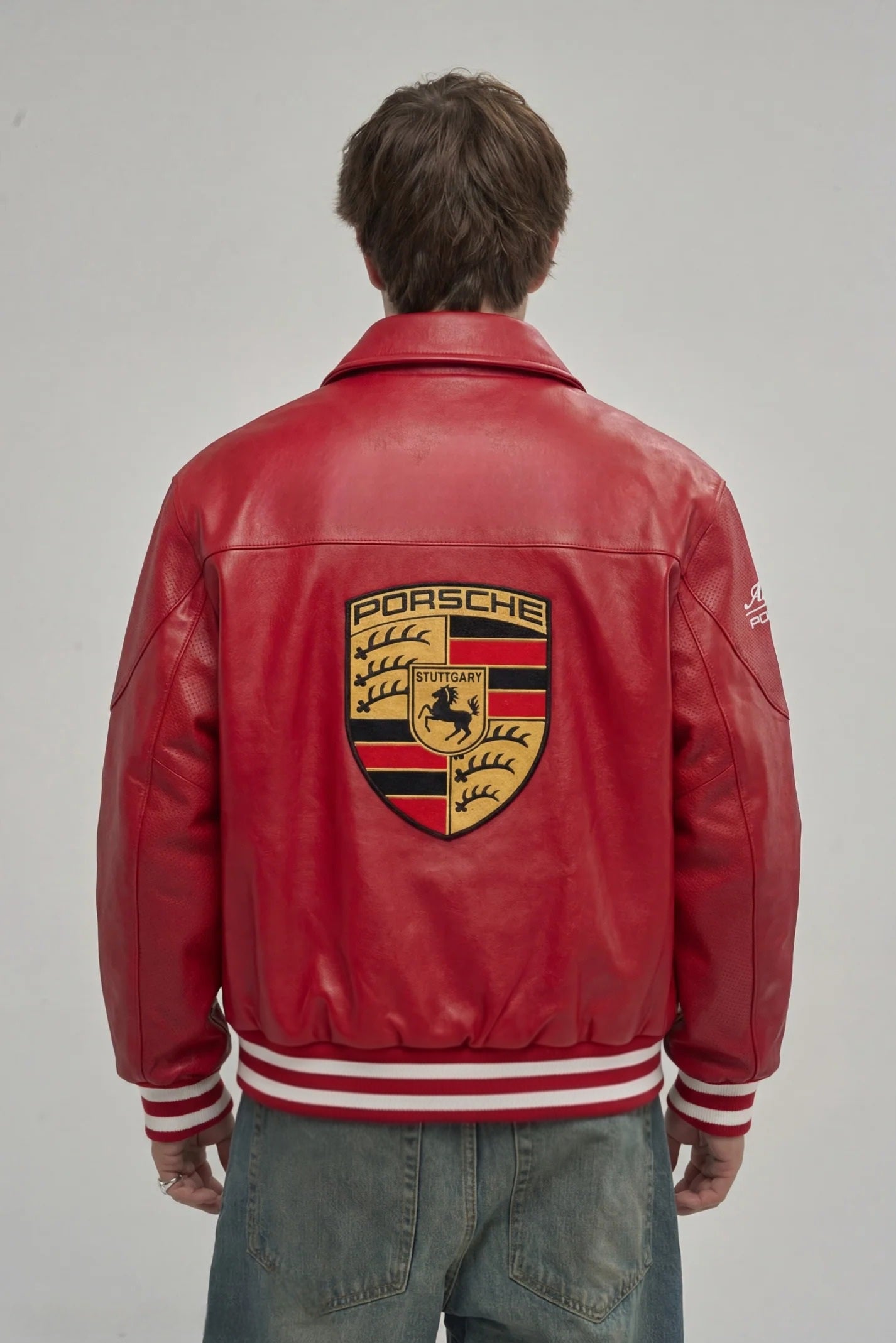 Back profile demonstrating the bold motorsport embroidery and structured cropped silhouette on the men's racing jacket