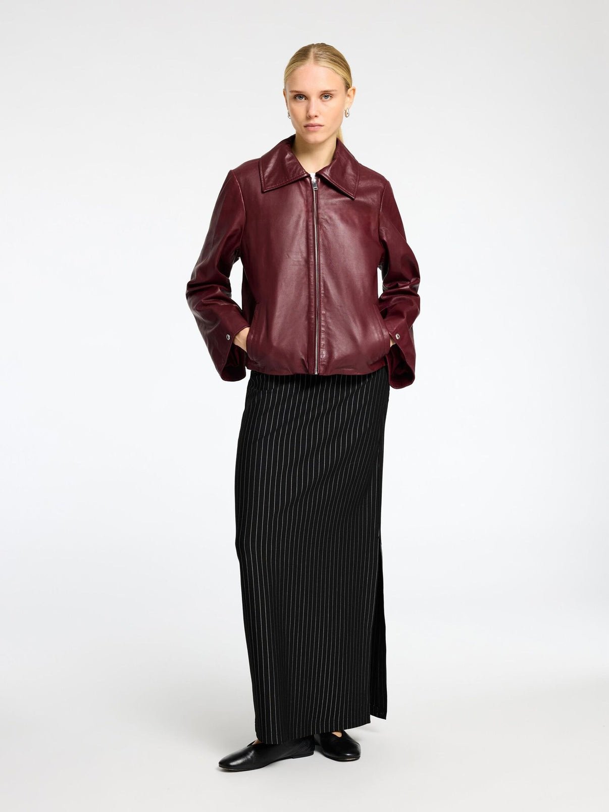 Urban streetwear lifestyle shot highlighting the proportions of the burgundy crop leather jacket paired with baggy denim