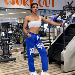 Woman wearing blue Trust Issue Printed Baggy Pants, styled with a white crop top, posing in a gym setting