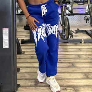 Female model in relaxed-fit Trust Issue Printed Pants, posing casually in a fitness center.