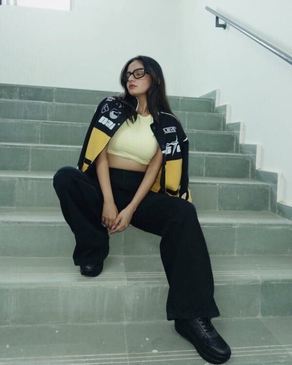 Anushka Sen seated, modeling the Exotix Naruto Jacket with vibrant yellow and black panels