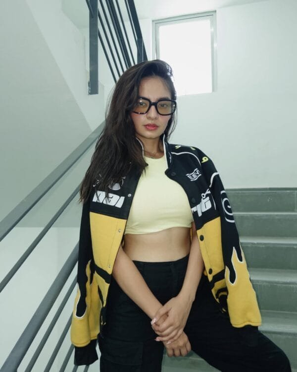 Anushka Sen posing in Exotix Naruto Flame Patch Jacket – front view showcasing bold black and yellow design with flame details on sleeves