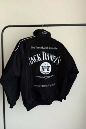 Black Jack Daniel's racing jacket displayed on a clothing rack. The back features bold white "Jack Daniel's Old No. 7 Brand" text, a Chevrolet logo on the collar, and the slogan "Pace Yourself. Drink Responsibly."