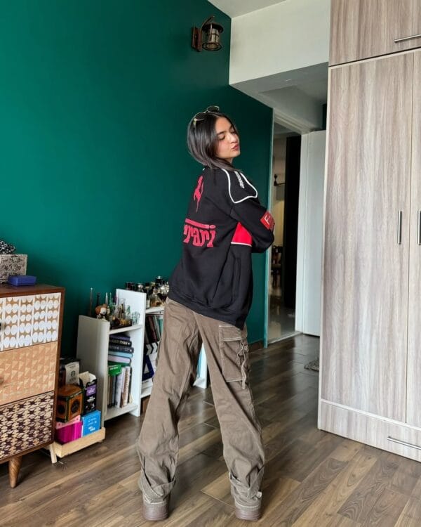 Model posing indoors wearing Ferrari jacket black with bold red branding and racing logos – Exotix Formula 1 merchandise