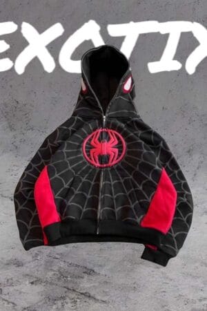A red and black Spiderman-style hoodie laid flat on a concrete background, showing spider web patterns and a black spider emblem, with “EXOTIX” written in bold white letters above.