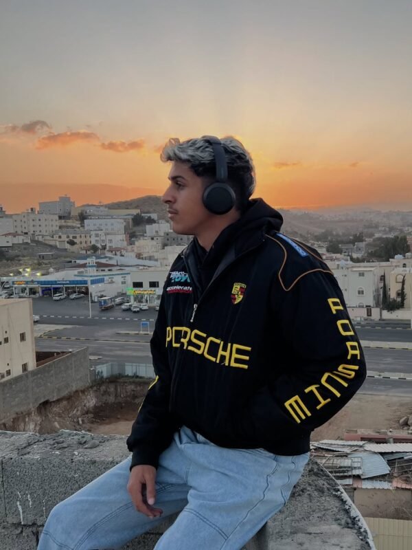 Model wearing black Porsche embroidered jacket by Exotix – luxury streetwear style