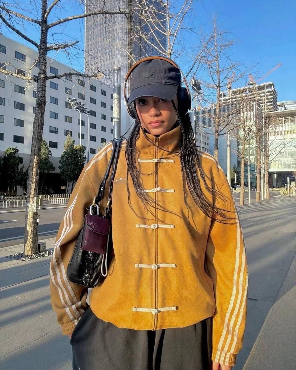 Chinese New Year Jacket – Exotix CNY Edition Model in mustard Exotix Chinese New Year jacket featuring traditional knot closures and striped sleeves, paired with cap and headphones on a city street.